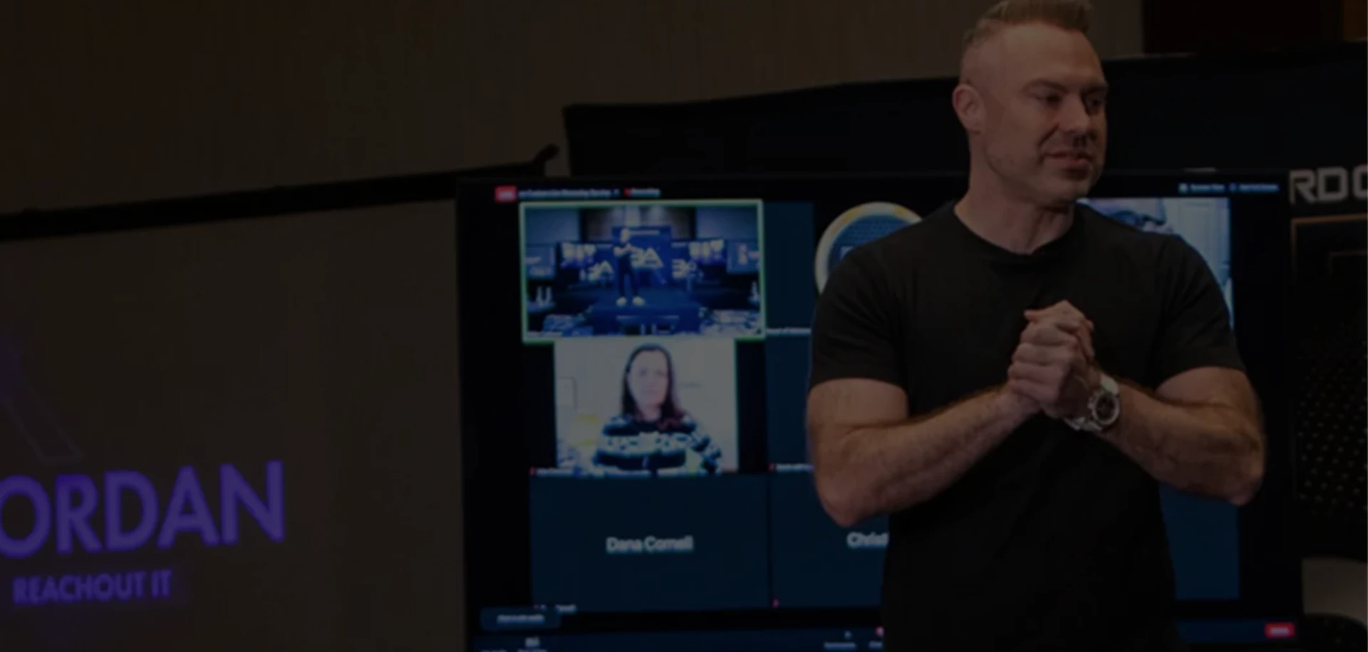 Rick Jordan speaking on stage in front of a video wall of remote MSP owners